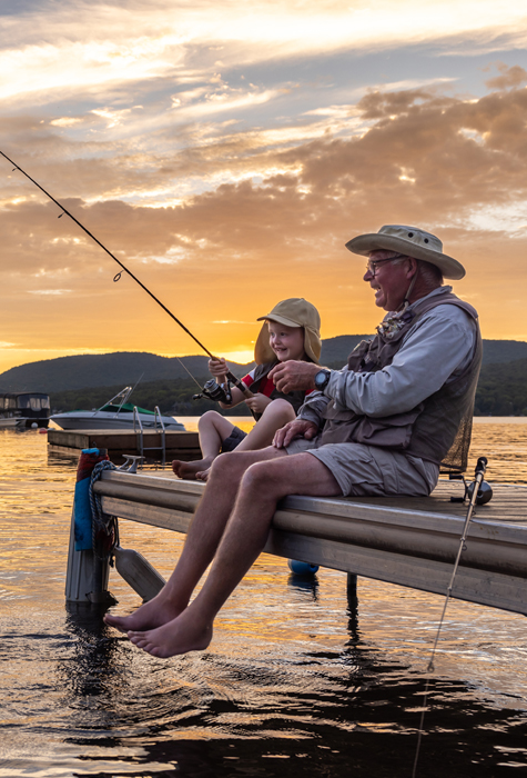 grandad and kid fishing in the sunset